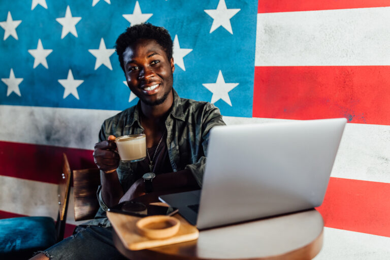 Photo of happy african man sitting in a cafe and working on laptop , have a coffe break..